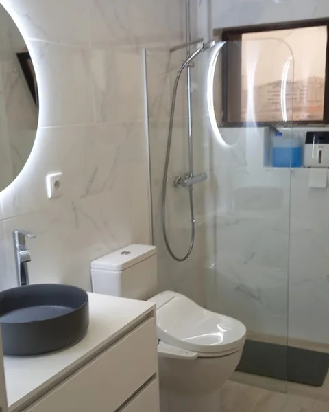 Remodelação de casa de banho de luxo no Algarve com paredes de mármore, duche com moldura preta e luz natural