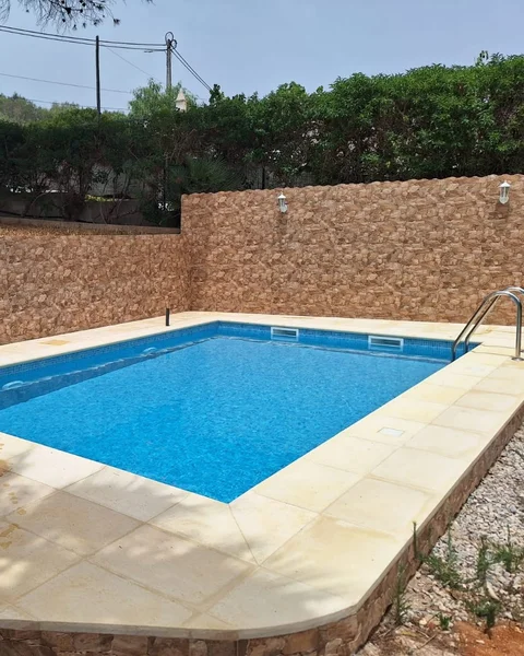 Instalação de piscina no Algarve com muro de pedra, liner azul e duche exterior